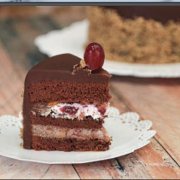 A slice of chocolate cake with cherry and cream filling, topped with a single red cherry.