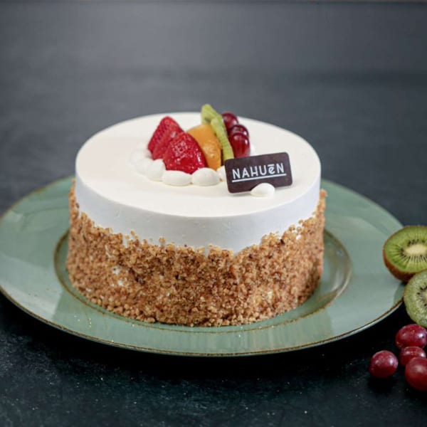 NAHUEN Gourmet Market's round cake with white frosting, nut-covered sides, and fresh fruit topping.