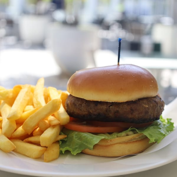 A Nahuen Gourmet Market burger with lettuce, tomato, and fries on a white plate.