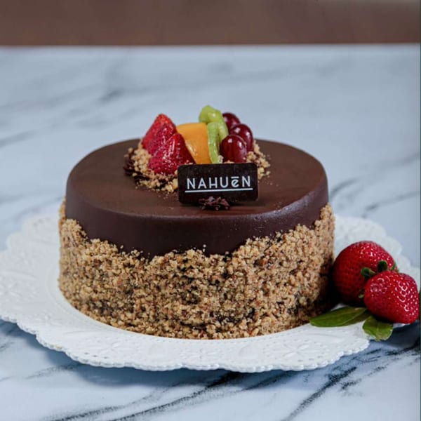 NAHUEN Gourmet Market's chocolate cake with nuts, fresh fruit, and strawberries on a white plate.