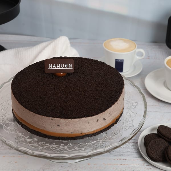NAHUEN Gourmet Market's chocolate and dulce de leche cake, topped with cookie crumbs, next to coffee.