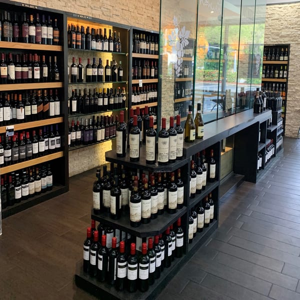 A wide selection of Argentinian wines displayed on dark shelves in a gourmet market.
