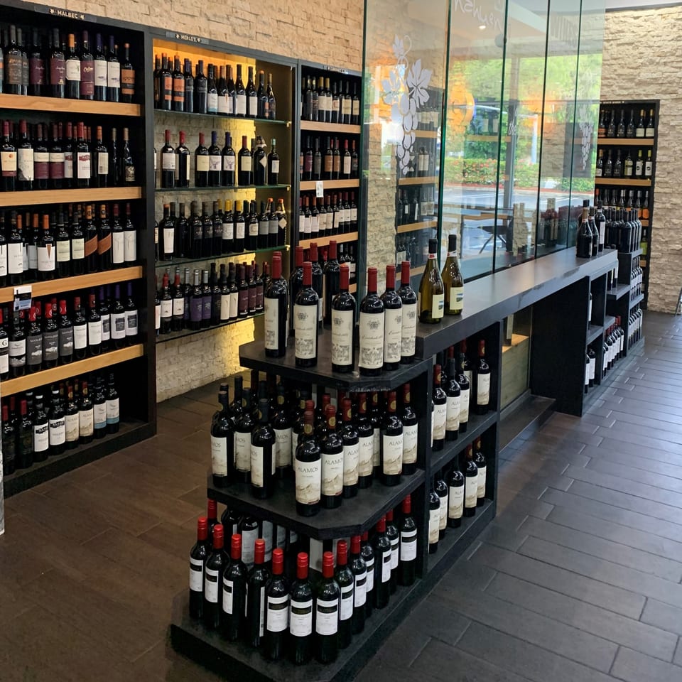 A wide selection of Argentinian wines displayed on dark shelves in a gourmet market.