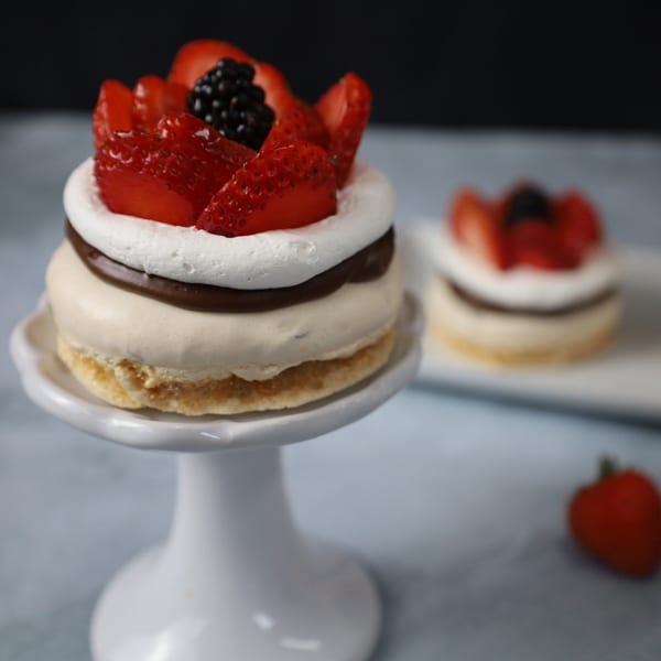 A Nahuen Gourmet Market dessert with meringue, chocolate, and fresh strawberries on a white stand.