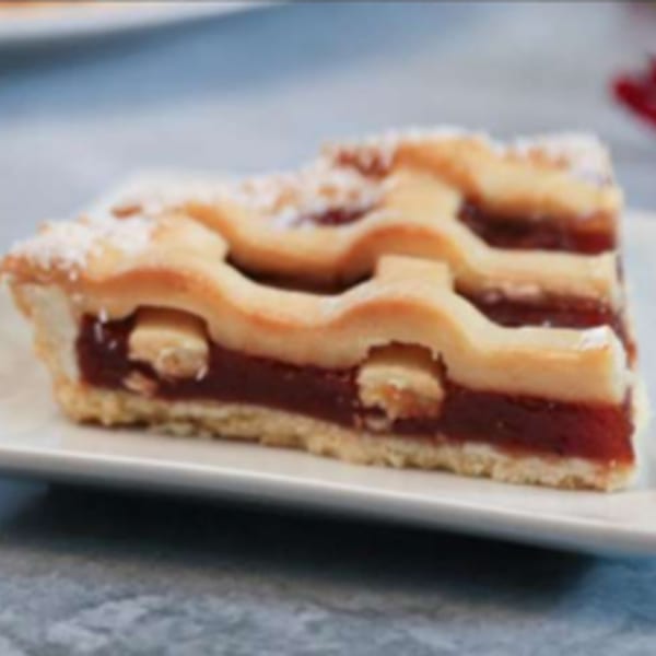 A slice of Argentinian pastafrola, a quince tart with a lattice crust, on a white plate.