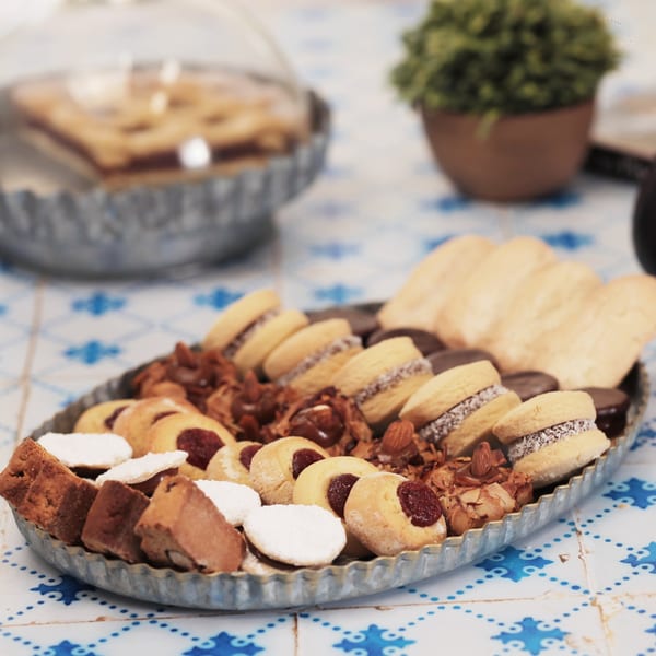 A metal tray filled with various Argentinian pastries, including alfajores and shortbread cookies.