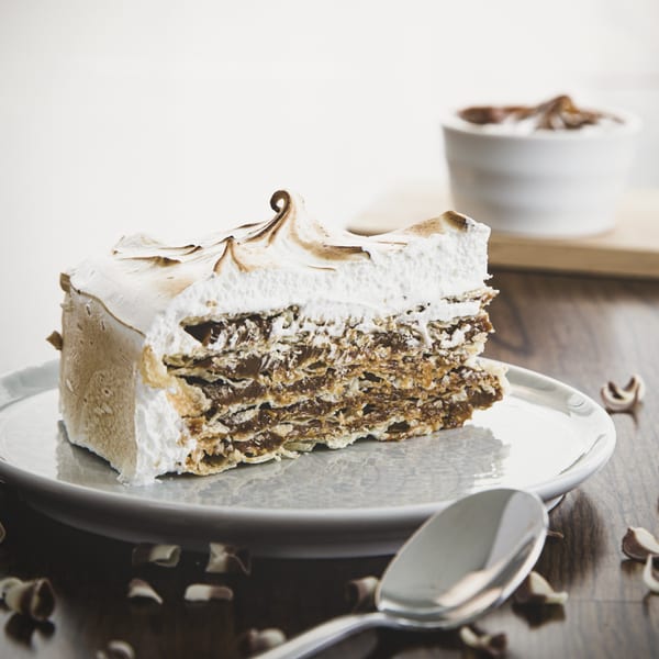 A slice of Argentinian Rogel cake with dulce de leche and meringue on a white plate.