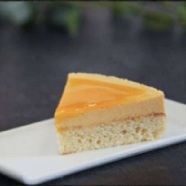 A slice of Argentinian dulce de leche cake with a glossy caramel topping on a white plate.
