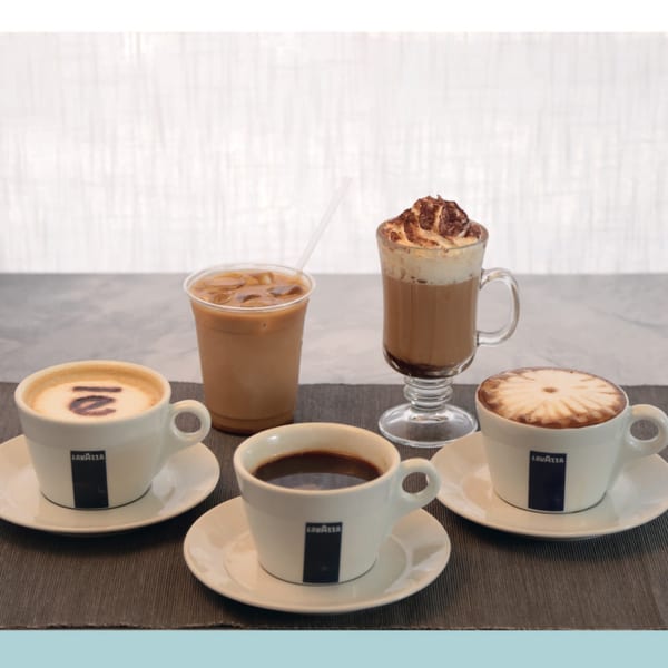 Four Lavazza coffee drinks: two lattes with art, an iced coffee, and a whipped cream mocha.