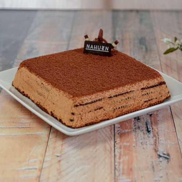 A rectangular chocolate cake with cocoa powder on top and a "NAHUEN" chocolate tag.